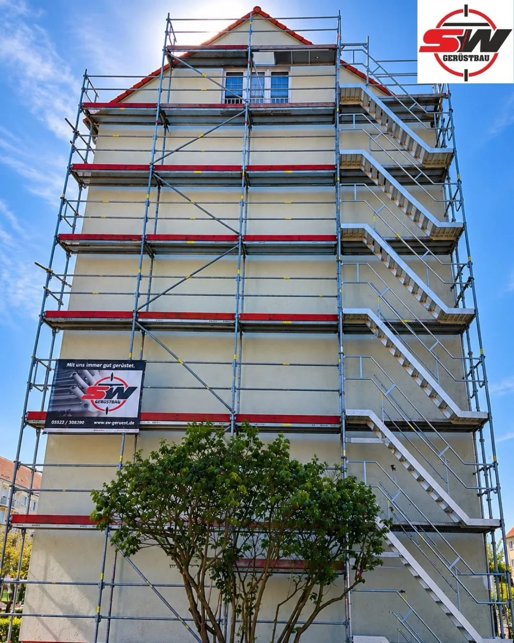 Vollständig montiertes Fassadengerüst mit Treppenzugang und SW-Gerüstbau-Banner